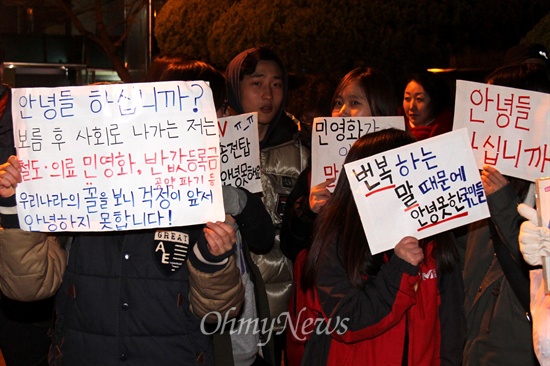  19일 저녁 창원 마산합포구 소재 경남대 정문 쪽에서 열린 "창원, 안녕하지 못한 사람들의 나들이" 행사에 참석한 사람들이 피켓을 들고 서 있다.