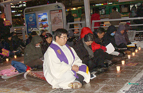 18대 대선 1주년을 맞은 19일 저녁 수원역 광장에서 열린 ‘부정선거 무효, 박근혜 정권 퇴진 촉구 시국기도회’에서 참석자들이 자리 앞에 촛불을 밝힌 채 기도하고 있다. 
