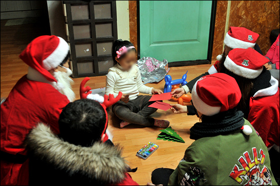 몰래산타에 참가한 대학생들이 크리스마스 카드를 써서 아이에게 전달하고 있다.