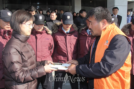  박석용 전국보건의료산업노동조합 진주의료원지부장이 23일 오전 경남도청 현관 앞에서 홍준표 지사한테 전달해달라며 정약용 선생의 <목민심서>를 윤성혜 경남도 복지보건국장(왼쪽)한테 전하고 있다.