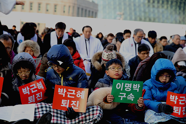 부모와 함께 성탄절 연합예배에 참석한 어린이들이 이명박 구속, 박근혜 퇴진 피킷을 들고 있다.