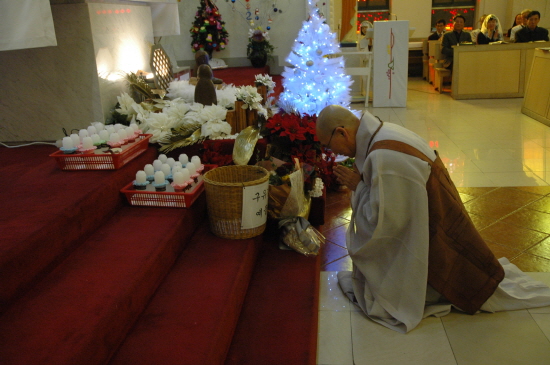 12월25일 쑥고개 성당에서 이뤄지는 성탄절 미사에 참석해 꽃을 헌화하고 기도하는 법륜 스님. 