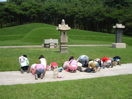 백범 60주기를 맞아 한 무리의 어린이들이 선생님을 따라 백범 묘소 앞에 꿇어 엎드려 절을 올리고 있다. (2009. 6. 26)