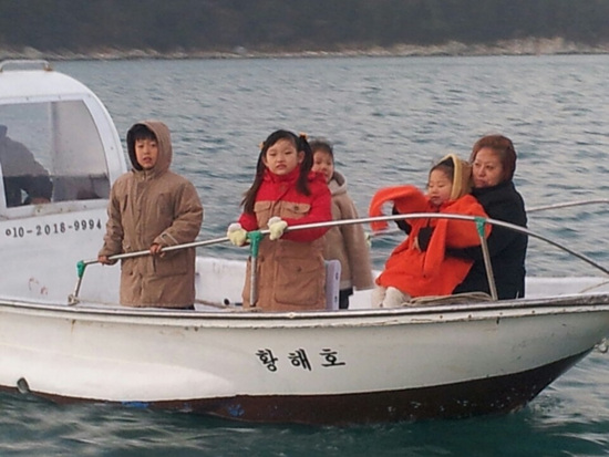 지체장애자 정인구씨(42세)의 가족이 <아빠어디가>의 촬영지 안도 동고지에서 배를 타고 해맞이를 보고 있다.
