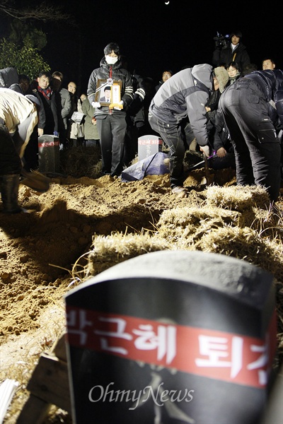 '박근혜 퇴진', '특검 실시'가 적힌 현수막을 내걸고 분신한 고 이남종(40, 광주 북구)씨가 4일 광주 북구 망월공원묘지(옛 5·18묘역)에서 영면에 들어갔다. 이씨의 영정사진을 든 동생 이상영씨 앞에서 인부들이 흙을 퍼 나르고 있다.
