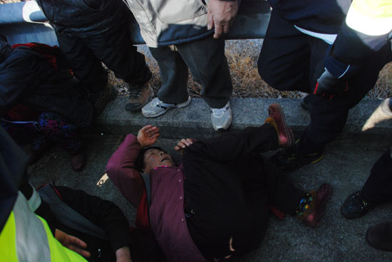 송전탑 건설 반대 주민이 경찰 진압 과정에서 콘크리트 바닥에 쓰러진 모습