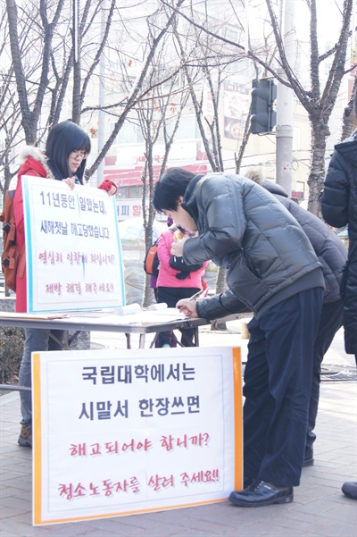 서울 노원구 서울과학기술대학교에서 일하다 계약을 거부당한 청소용역업체 직원 2명이 학교 앞 정문에서 서명운동을 벌이고 있다.