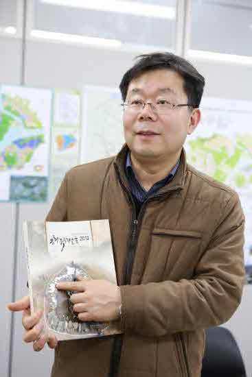 행복청 학예연구관인 김교년 박사가 최근 발간한 '문화유적 발굴 2013' 책자를 들어보이고 있다. (사진:행복청 제공)