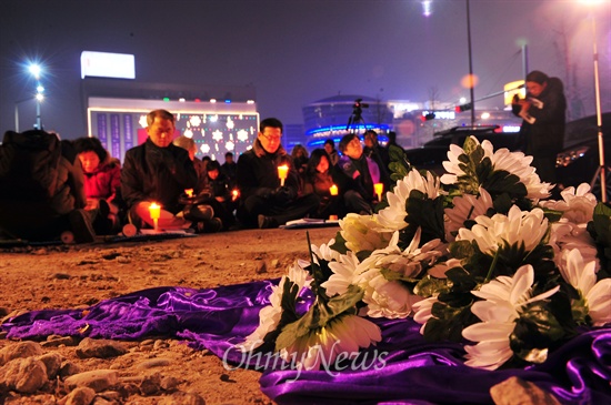  16일 오후 서울 용산구 남일당터에서 열린 '용산참가 5주기 추모예배'에서 고인들에게 헌화한 국화 뒤로 참가자들이 기도를 하고 있다.