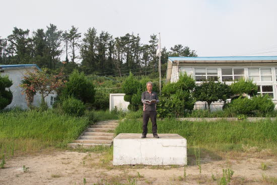 바닷에 있는 학교  조회대 위에 서 있는 관광객 