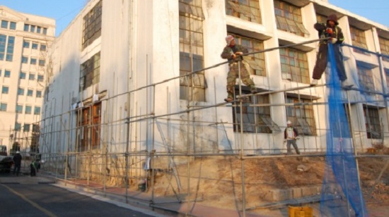 비계공들이 건물 철거 장막을 설치하기 위해 비계를 조립하고 있다. 
사진은 2009년께 찍은 사진.