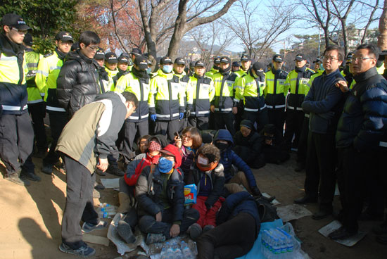 경찰에 끌려나온 주민들이 경찰 앞에 앉아 있다.