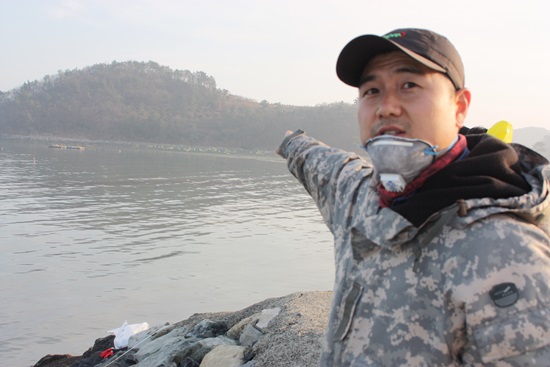 신덕마을 대책위원인 강중안(38세)씨가 손가락 너머로 방재작업이 진행중인 바지락 양식장을 가르키며 '특별 재난구역'으로 선포되어야 한다고 요구하고 있다.
 
