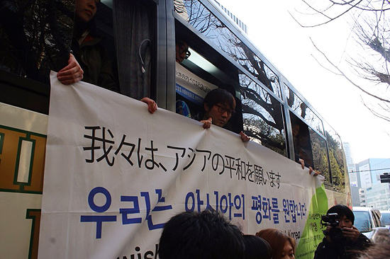 2·8 도쿄원정대가 버스 안에서 '우리는 아시아의 평화를 원합니다' 현수막을 들고 있다. 