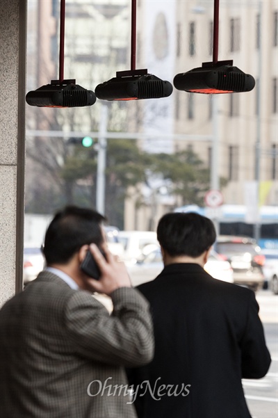 12일 오전 서울 중구 한 호텔의 온열기 아래서 손님들이 추위를 피하고 있다.