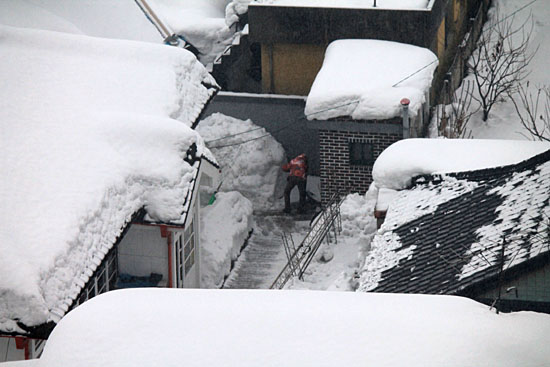 눈에 덮인 강릉, 한 시민이 집 안에 쌓인 눈을 치우고 있다.