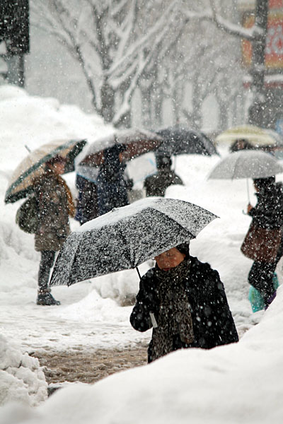 눈이 내리는 거리를 바쁘게 걸어가는 시민들.