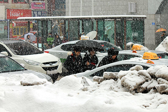 금성로, 눈이 내리는 도로 위로 차와 사람들이 뒤엉켜 있다.