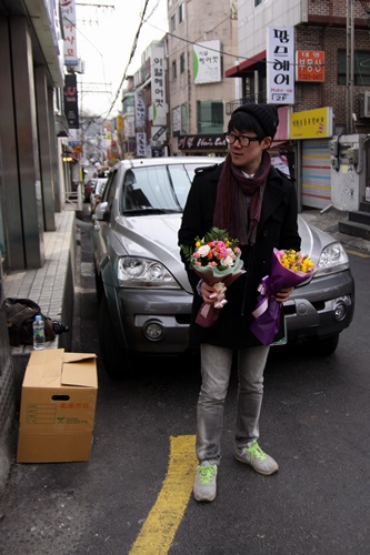 기자가 남은 꽃 두 다발을 손에 들고 판매에 열을 올리고 있다.