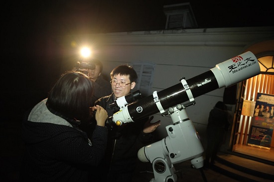  한 참가자가 전문가의 지도하에 천문망원경을 통해 별을 보고 있다