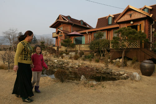 김은심 씨가 큰 손녀와 함께 집앞 마당을 걷고 있다. 남편 김태제 씨가 손수 설계한 통나무집이다. 마당에 연못도 파 놓았다.