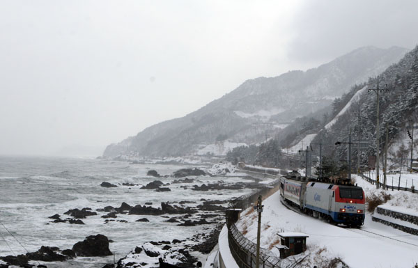 바다와 가까운 철도. 눈 내리는 바닷가를 달리는기차.