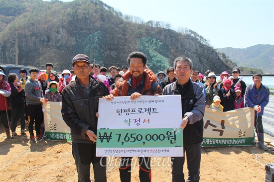  밀양 송전탑 반대 주민과 '밀양 송전탑 공사 중단 및 백지화를 위한 경남공동공대책위원회'는 6일 오전 밀양시 단장면 용회마을에서 "밀양 765kV 송전탑 결사 반대, 밀양과 함께 하는 '한 평 프로젝트' 개장식'을 가졌다. 사진은 김재명 민주노총 경남본부장이 김정회(동화), 박호야(용회) 마을이장한테 '765만원 약정서'를 전달하는 모습.