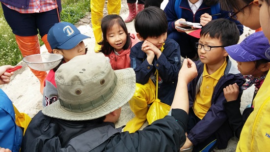 잠자리 유충의 날카로운 턱을 보여주고 계신 선생님, 구경하는 아이들의 표정이 다채롭습니다.