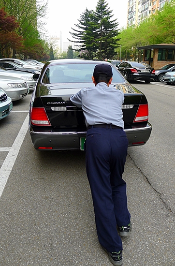 경비 노동자가 차를 미는 모습(자료 사진)