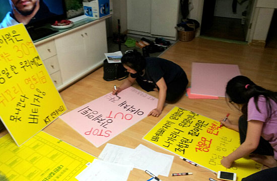 KT 직원 이우현씨 가족들이 강제 명예퇴직 반대 1인 시위에 사용할 피켓을 만들고 있다.