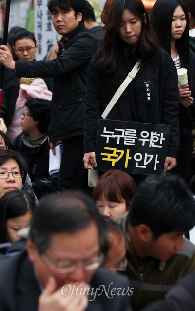 300여개 시민사회단체로 구성된 국정원시국회의가 19일 저녁 서울 종로구 청계광장에서 4·19 54주년을 기념한 범국민대회를 열었다. 이날 대회 참가자들은 "4·19 혁명이 일어난 날을 맞아 여러가지 목소리가 표현돼야 할 날이지만 세월호 침몰 피해자들의 무사생환을 염원하는 마음이 무엇보다도 우선"이라고 밝혔다. 대회에 참가한 한 고등학생이 고개를 떨군 채 '누구를 위한 국가인가'라는 피켓을 들고 있다. 