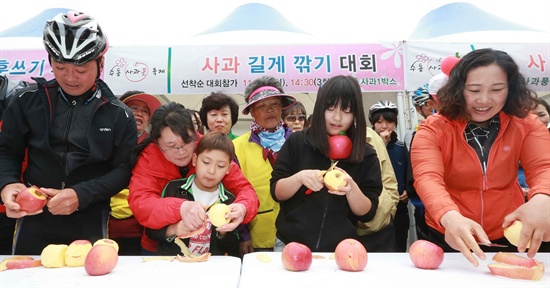  19일 오후 경남 함양군 수동면 도북리에서 제1회 수동사과꽃축제가 열린 가운데 관광객들이 사과 길게 깎기를 하고 있다.