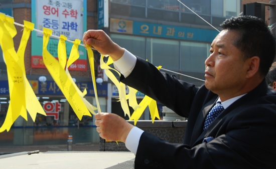    이창선 공주시의회 부의장이 24일 공주 중동사거리에서 '노란리본달기 캠페인'에 동참하며 세월호 침몰 참사 실종자들의 무사귀환을 바라는 마음을 담은 기원메세지를 달고 있다.