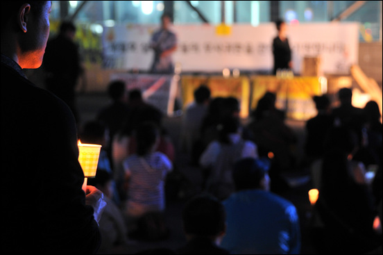 지나가던 시민이 발길을 멈추고 세월호 무사귀환을 염원하며 촛불을 들고 서있다.