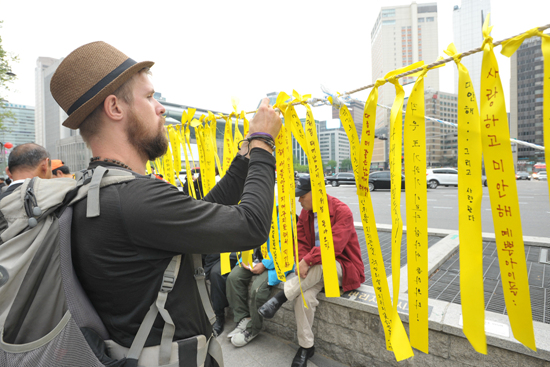 26일 오후 서울 중구 대한문 앞에서 한 외국인이 '세월호 침몰사고;로 인한 희생자들을 애도하고 실종자들의 무사귀환을 염원하는 노란끈을 묶고있다.
