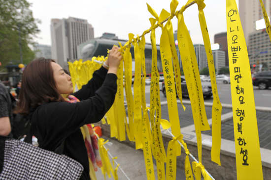 26일 오후 서울 중구 대한문 앞에서 한 시민이 '세월호 침몰사고'로 인한 희생자들을 애도하고 실종자들의 무사귀환을 염원하는 노란끈을 묶고 있다.