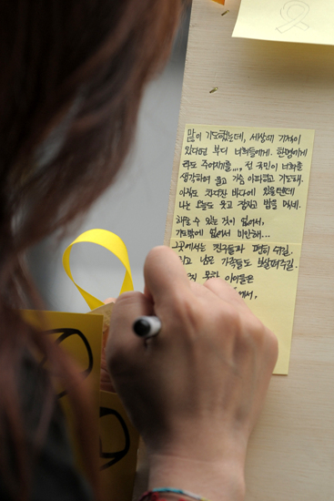 26일 오후 서울 광화문 동화면세점 앞에서 한 시민이 '세월호 침몰사고'로 인한 희생자들을 애도하고 실종자들의 무사귀환을 염원하는 글을 적고 있다.