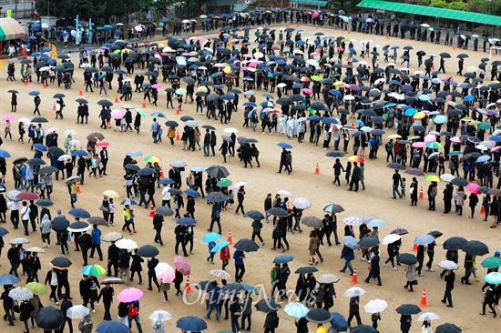  우산을 쓴 조문객들이 차분하게 줄지어 가고 있다.