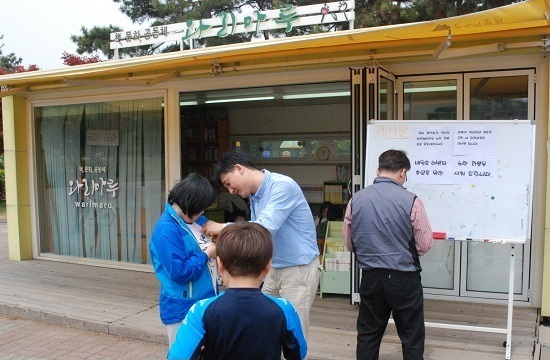 김은호 목사가 와리마루 도서관을 찾은 아이들에게 노란리본을 달아주고 있다. 오른편 게시판에 ‘임시봉안소가 설치될 와동체육관을 노란리본으로 물들여 주십시요’라는 안내문이 적혀 있다. 