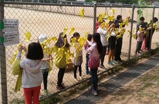 동네 어린들이 부모와 함께 단원고 희생 학생들의 합동영결식이 거행되는 와동체육관 임시봉안소 옆 철조망에 노란리본을 매달며 언니, 오빠, 형, 누나의 무사귀환을 기원하고 있다.