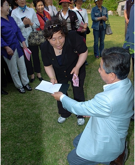 2008년 5월 21일 사저 앞 잔디밭에서 방문객 인사를 받던 노 대통령이 한 여성으로부터 사인을 요청받자 무릎을 꿇고 사인을 해주고 있다. 