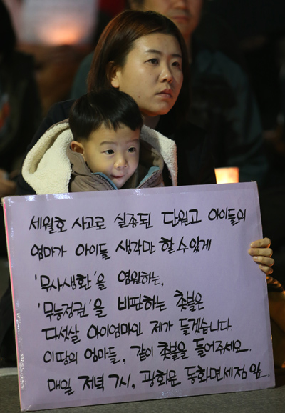 전국여성연대 주최로 지난 21일 저녁 서울 세종대로 동화면세점 앞에서 열린 세월호 실종자 무사생환 기원 시민 촛불 행사에서 한 시민이 아이와 함께 기원 메시지를 들고 있다. 