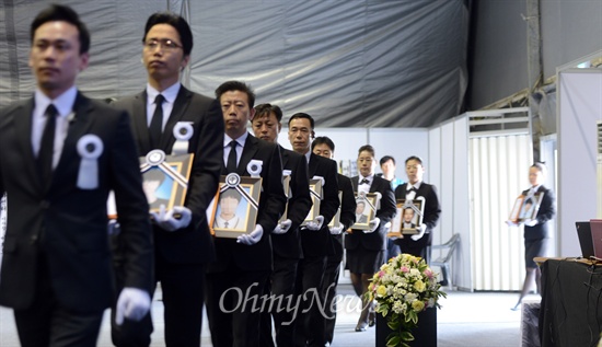 2014년 5월 1일 오전 경기도 안산시 화랑유원지에 마련된 '세월호 사고 희생자 정부 합동분향소'에서 장례진행 요원들이 희생자들의 영정사진을 옮기고 있는 모습.