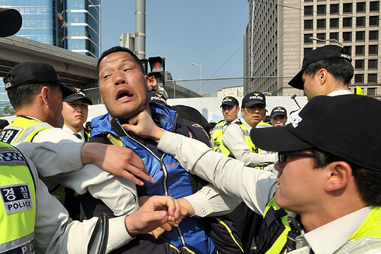  '2014년 세계노동절대회'를 끝마친후 거리행진을 시도하는 장애인들과 이를 저지하는 경찰들이 충돌하는 과정에서 한 경찰관이 주먹으로 장애인의 목을 치며 밀어내고 있다.