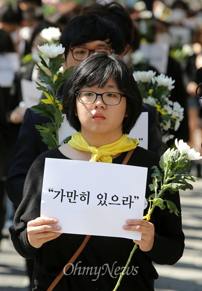 세월호 참사 희생자 추모와 무책임한 정부를 규탄하는 시민들이 지난 2014년 5월 3일 오후 서울 마포구 홍대입구역 부근에서 '가만히 있으라'가 적힌 손피켓과 국화꽃을 들고 침묵시위를 벌이고 있다.