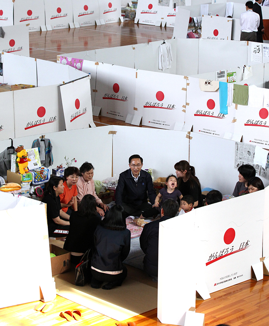 지난 2011년 5월 21일 이명박 대통령이 아즈마 종합운동공원에 차려진 후쿠시마 이재민 피난소를 방문했을 때의 모습. 피난소 내에는 포장박스로 개인공간을 확보해 놓았다. 포장 박스에는 "힘내라 일본"이라고 쓰여져 있다.  
