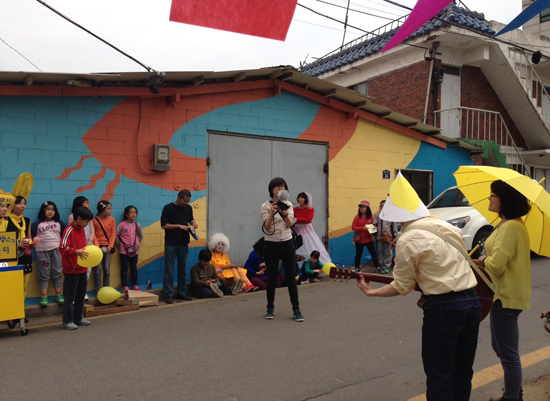 축제의 일환으로 그려진 벽화 앞에서, 행진을 마무리하는 노래를 부르고 있다.  