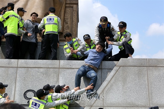세종대왕 동상에 올라간 학생이 경찰에 의해 끌려내려오고 있다.