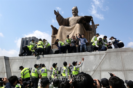 세종대왕 동상에 올라간 대학생들이 구호를 외치고 있다.