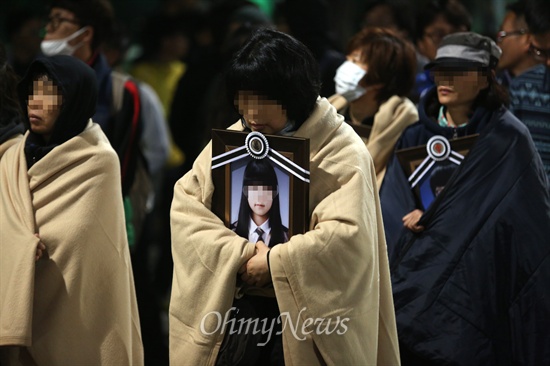 세월호 참사 유가족들이 안산 합동분향소에서 가져온 영정사진을 품은 채 5월 9일 새벽 박근혜 대통령 면담을 요구하며 청와대를 향해 걸어가고 있다.